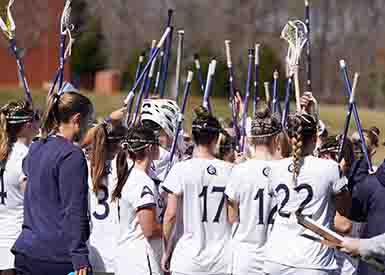 Female student athletes in lacrosse huddle