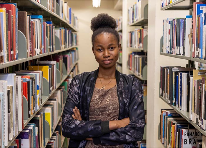 Student standing between library stacks